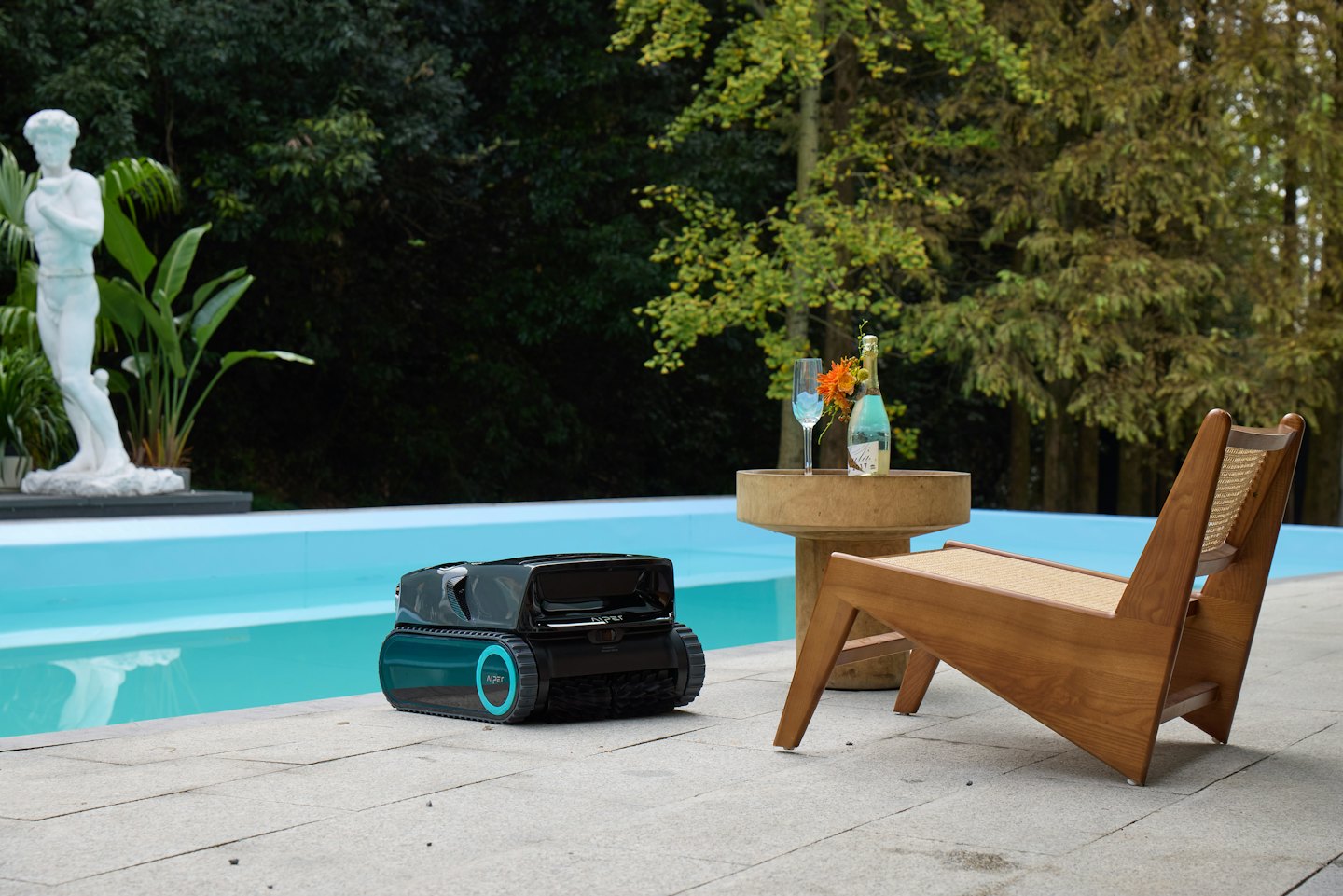 A pool cleaning robot sits on a patio by a pool.